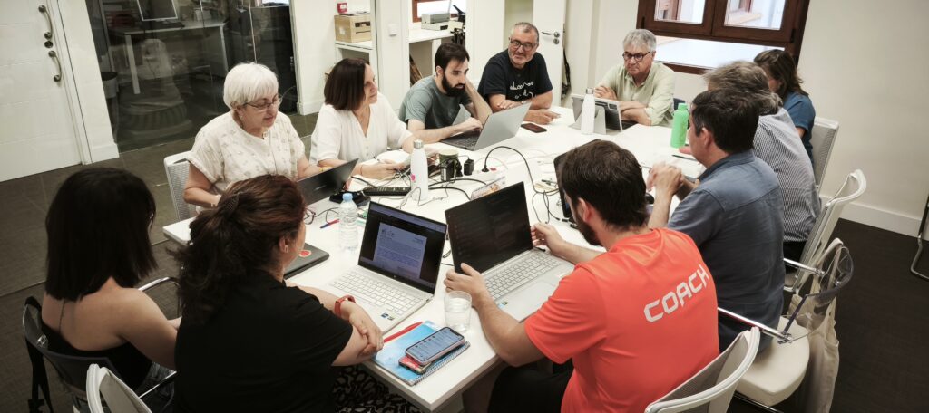 Group of people around a conference table with laptops, collaborating in a meeting at a modern office.
