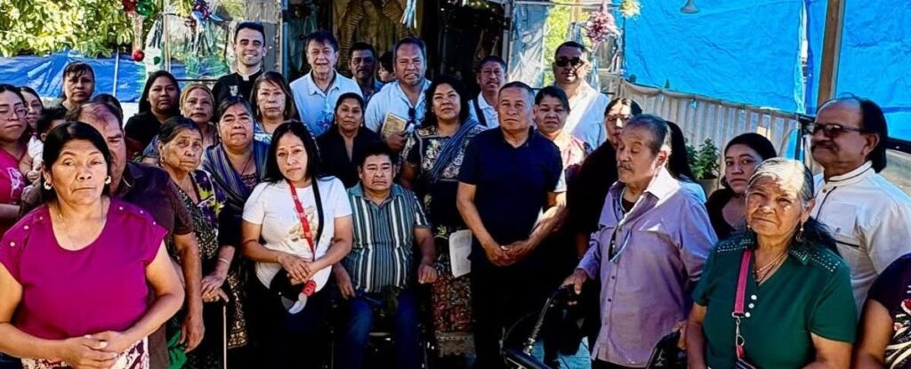 Group of men and women of various ages standing together outdoors at a community gathering.