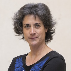 Portrait of a middle-aged woman with short gray hair wearing a black top with blue embroidery.