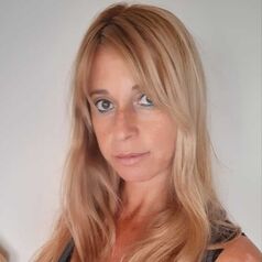 Portrait of a woman with long blonde hair, looking at the camera against a neutral background.